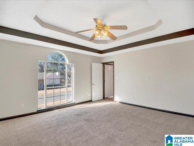 carpeted spare room featuring baseboards, a tray ceiling, ceiling fan, and a textured ceiling