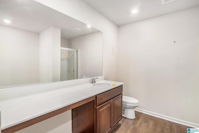 bathroom featuring toilet, wood finished floors, vanity, baseboards, and a stall shower