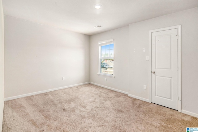 carpeted spare room featuring visible vents and baseboards