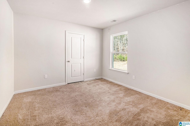 spare room with light carpet, baseboards, and visible vents