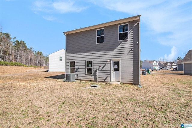 rear view of house featuring central AC and a lawn