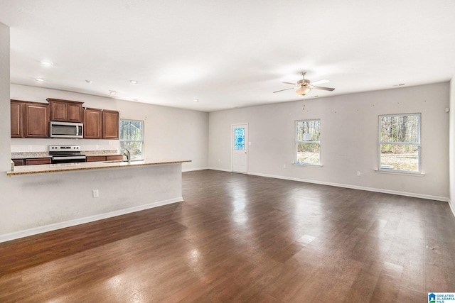 interior space featuring dark wood-style floors, a wealth of natural light, a sink, and baseboards