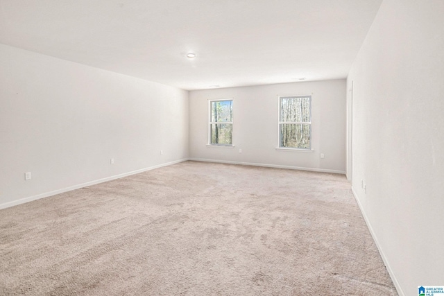 unfurnished room with baseboards and light colored carpet