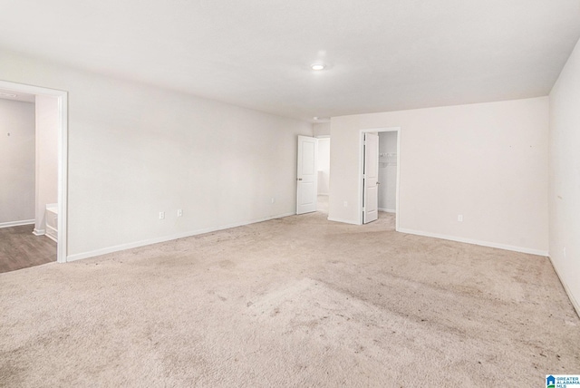 unfurnished bedroom with a spacious closet, baseboards, a closet, and light colored carpet