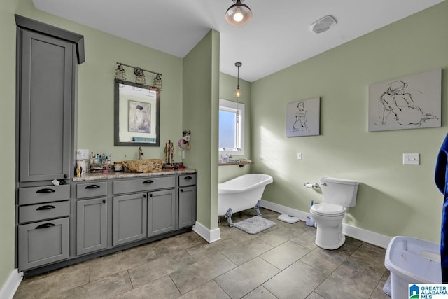 full bath with a freestanding tub, toilet, vanity, baseboards, and tile patterned floors