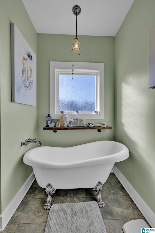 bathroom with a freestanding bath and baseboards