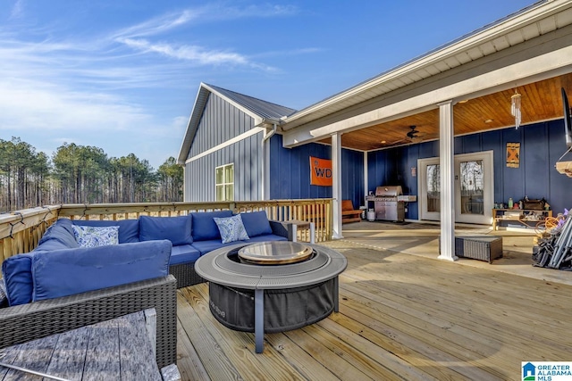 wooden terrace with grilling area and an outdoor living space with a fire pit