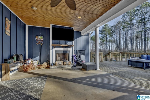 view of patio with ceiling fan, a deck, and exterior fireplace