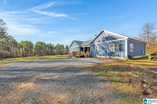 view of front of house featuring board and batten siding, gravel driveway, and a deck