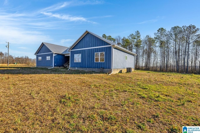 view of home's exterior with board and batten siding, a yard, and central AC unit