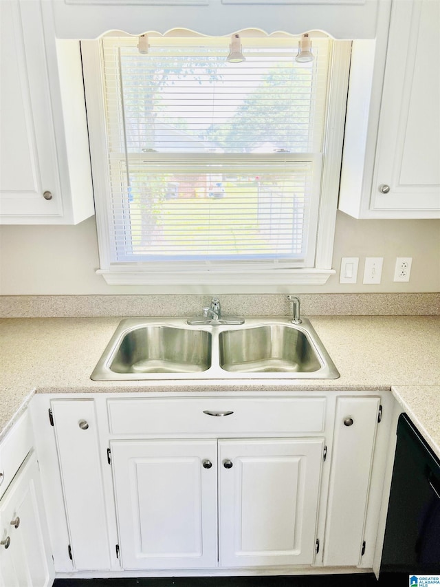 kitchen with a wealth of natural light, black dishwasher, white cabinets, and a sink