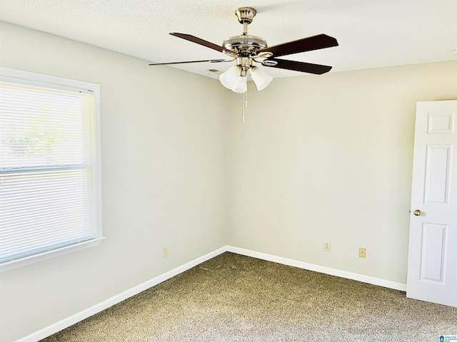 carpeted empty room with ceiling fan, a textured ceiling, and baseboards