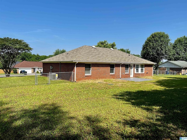 back of house with a shingled roof, fence, a yard, central AC, and brick siding