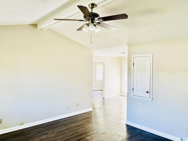 empty room featuring lofted ceiling with beams, dark wood-style floors, baseboards, and a textured ceiling