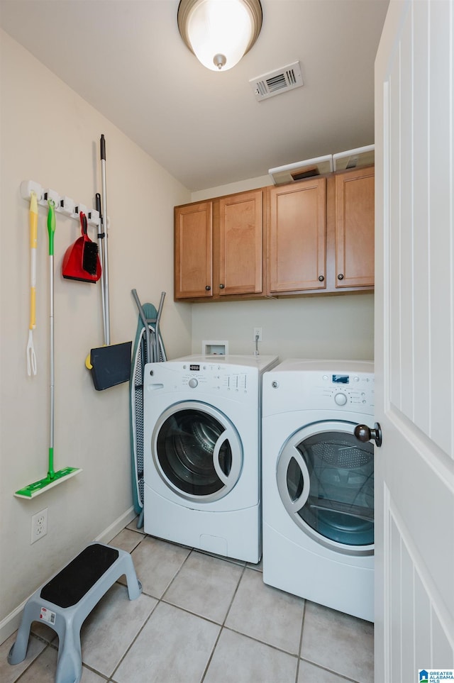 laundry area featuring washing machine and dryer, visible vents, cabinet space, and light tile patterned flooring