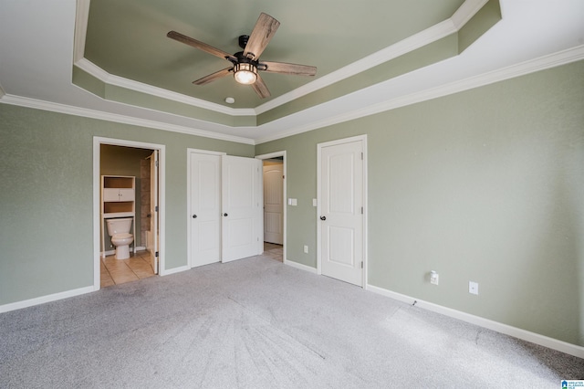 unfurnished bedroom featuring carpet floors, a raised ceiling, and baseboards