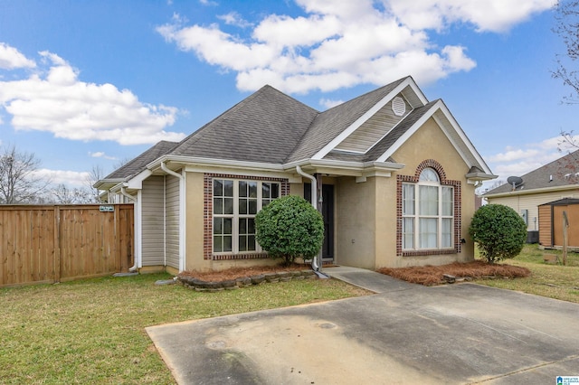 view of front of house featuring brick siding, roof with shingles, fence, and a front yard