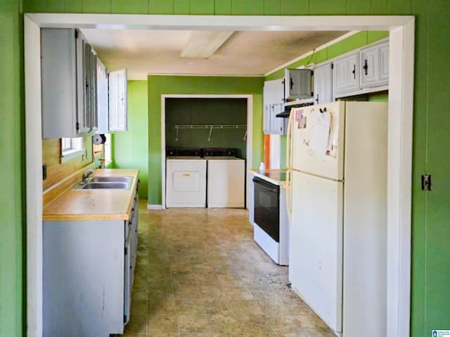 kitchen with electric range, freestanding refrigerator, light countertops, washer and dryer, and a sink