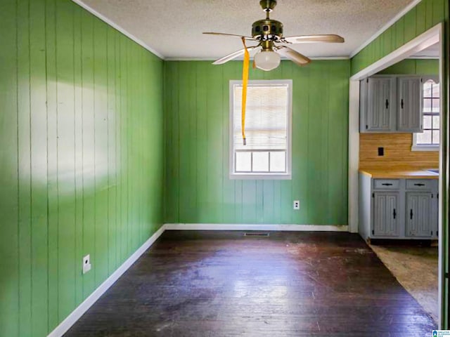 unfurnished dining area with crown molding, a textured ceiling, baseboards, and wood finished floors