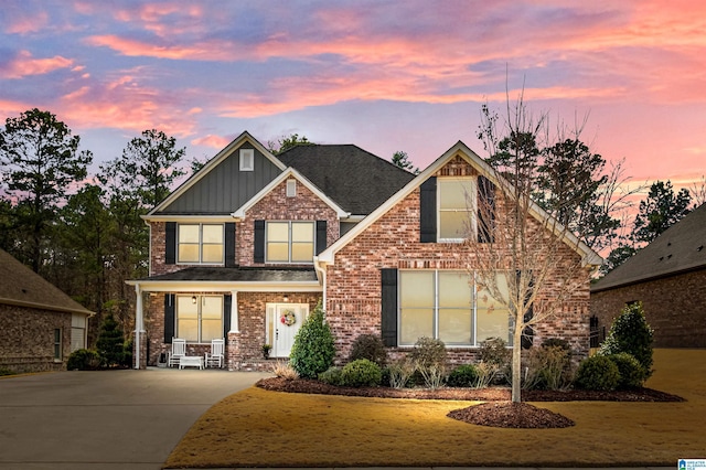 craftsman-style house with driveway, a front yard, board and batten siding, and brick siding