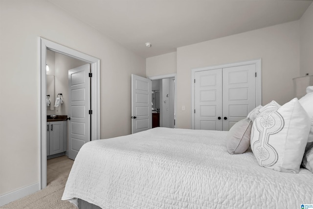 bedroom with connected bathroom, baseboards, a closet, and light colored carpet