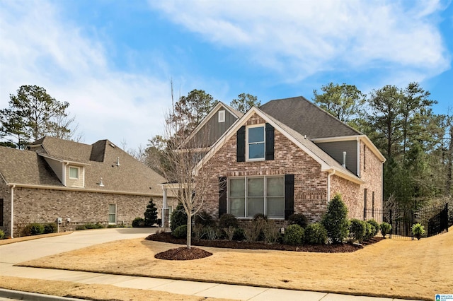 view of front of property with concrete driveway, brick siding, and fence