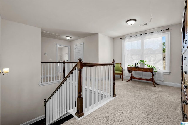 hallway with visible vents, baseboards, carpet flooring, and an upstairs landing