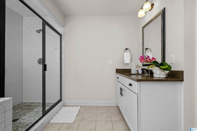 full bath featuring tile patterned flooring, a shower stall, vanity, and baseboards