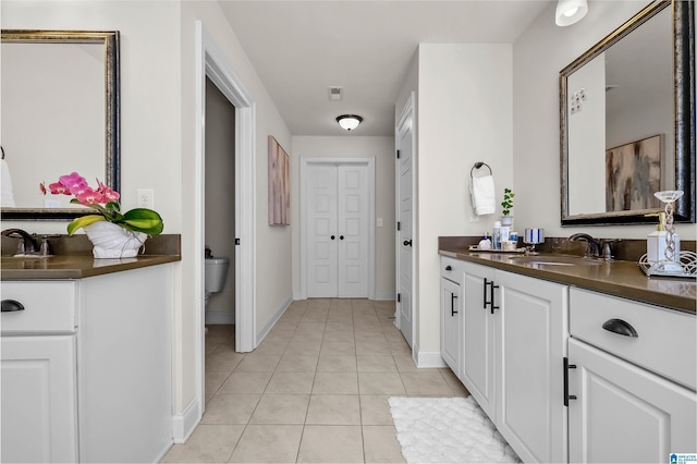 bathroom featuring toilet, tile patterned flooring, vanity, and baseboards