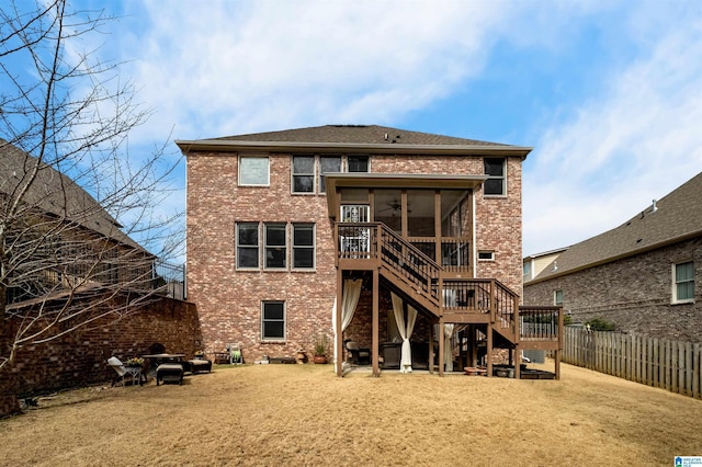 rear view of property with a ceiling fan, a sunroom, a fenced backyard, stairway, and brick siding