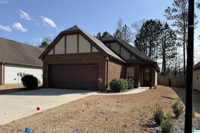 tudor home with brick siding, stucco siding, fence, a garage, and driveway