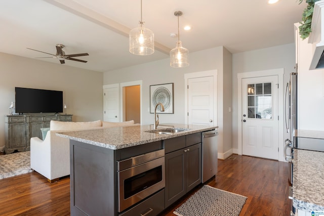 kitchen featuring dark wood-style floors, pendant lighting, stainless steel appliances, a sink, and light stone countertops