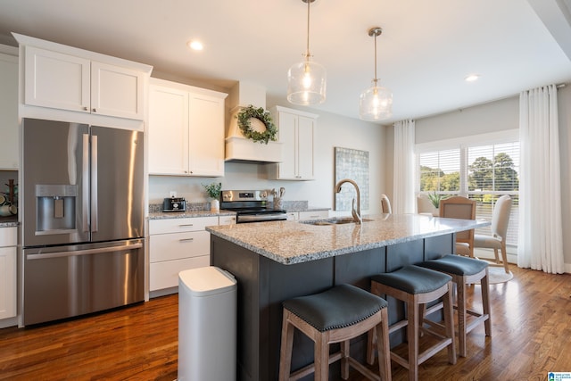 kitchen featuring white cabinets, dark wood finished floors, appliances with stainless steel finishes, a breakfast bar, and a sink