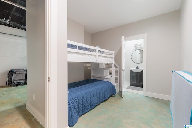 bedroom featuring baseboards, a sink, ensuite bath, and unfinished concrete floors