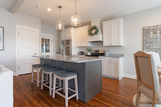 kitchen with stainless steel appliances, custom range hood, a kitchen island with sink, white cabinets, and a sink