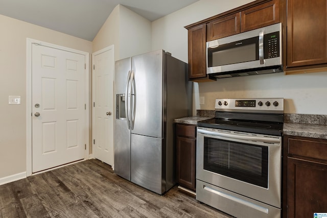 kitchen featuring dark brown cabinetry, stainless steel appliances, baseboards, dark wood-style floors, and dark countertops