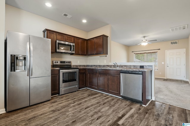 kitchen with a peninsula, appliances with stainless steel finishes, a sink, and visible vents