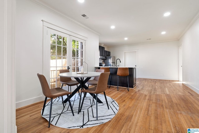 dining room with crown molding, visible vents, and light wood finished floors