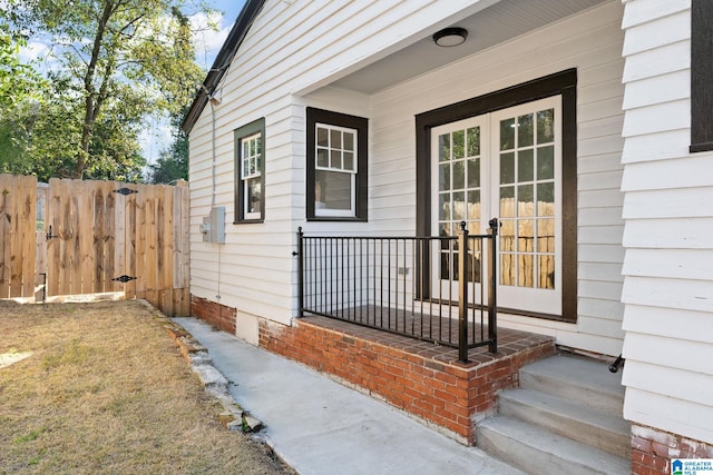 view of exterior entry featuring french doors and fence