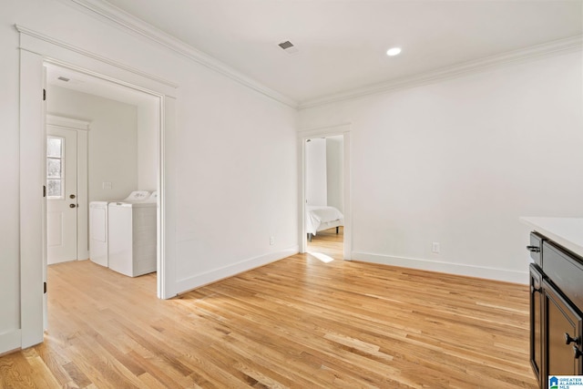 spare room featuring visible vents, crown molding, baseboards, light wood-type flooring, and independent washer and dryer