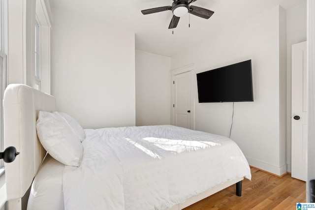 bedroom with light wood-type flooring, baseboards, and a ceiling fan