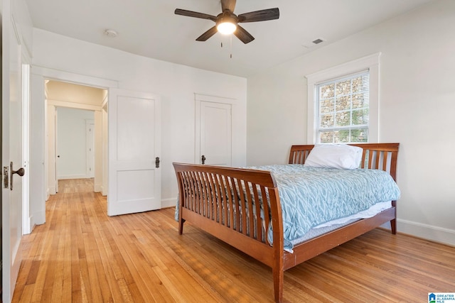 bedroom featuring ceiling fan, light wood-style floors, visible vents, and baseboards