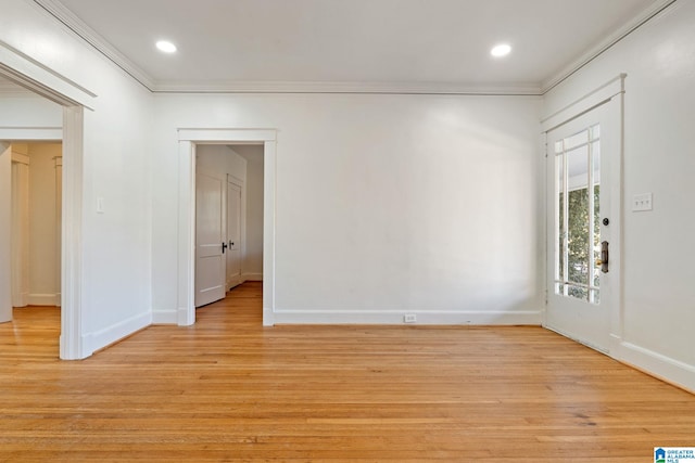 spare room featuring crown molding, light wood-style floors, and baseboards