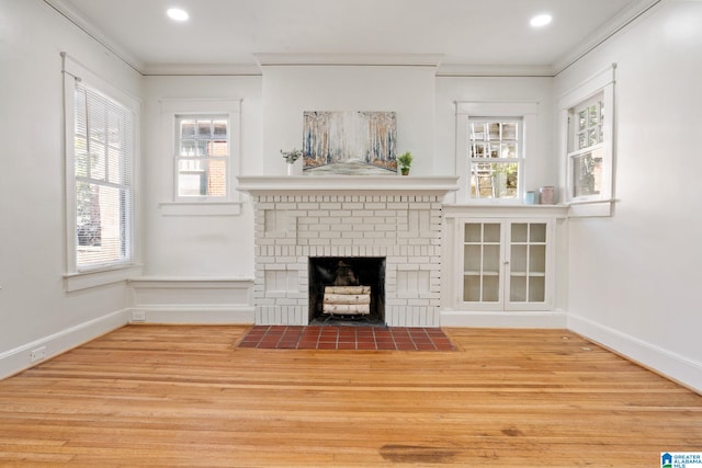 unfurnished living room featuring baseboards, a brick fireplace, wood finished floors, and crown molding