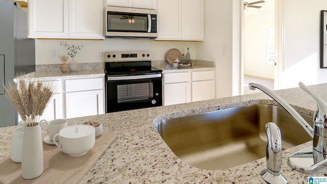 kitchen with appliances with stainless steel finishes, white cabinets, and a sink