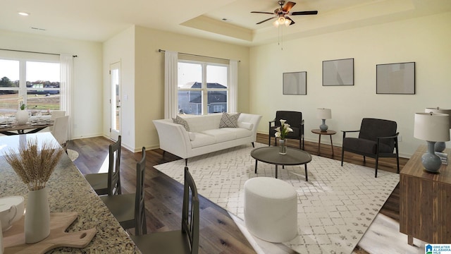 living room with baseboards, a tray ceiling, ceiling fan, and wood finished floors