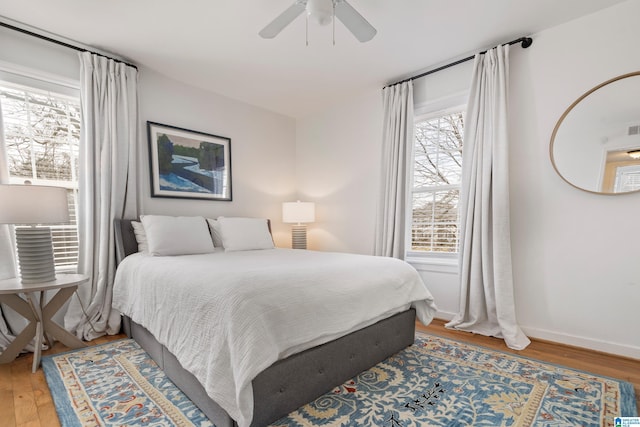 bedroom featuring light wood finished floors, a ceiling fan, and baseboards