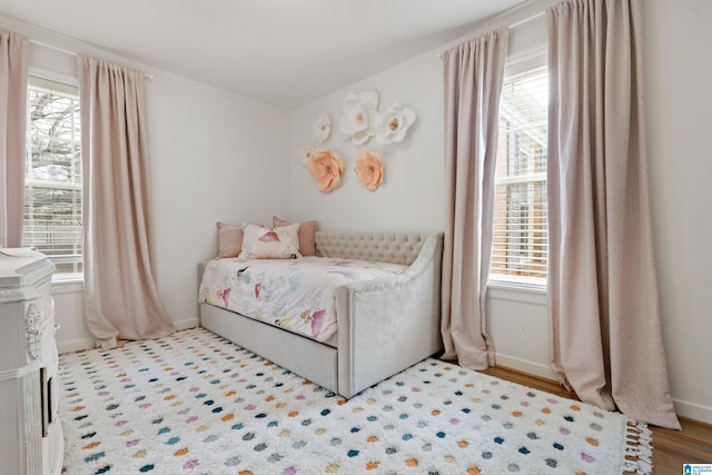 bedroom with baseboards, multiple windows, and wood finished floors