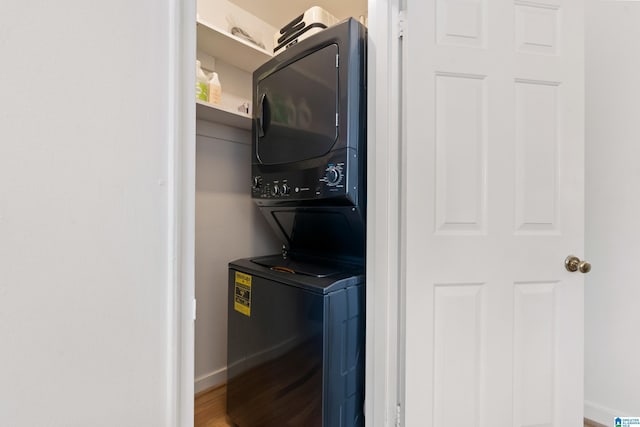 washroom featuring baseboards, wood finished floors, laundry area, and stacked washer / dryer