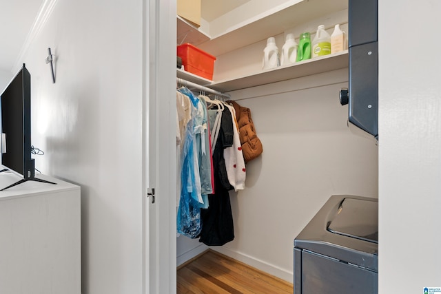 clothes washing area with laundry area, washing machine and dryer, wood finished floors, and baseboards